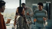 a group of people are standing in a living room with the word hulu on the bottom right
