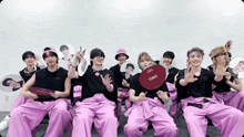 a group of young men wearing pink pants and black shirts with a fan that says tchiki on it