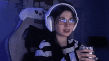 a woman wearing headphones and glasses is holding a glass of water