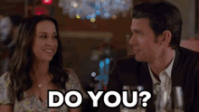 a man and woman are sitting at a table and the man is asking the woman do you
