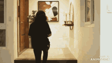 a woman in a black shirt is walking down a hallway with the words made in animatica on the bottom