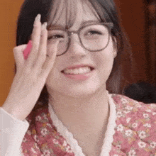 a close up of a woman wearing glasses and a floral dress .