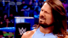 a wrestler with long hair and a beard is smiling in a wrestling ring .