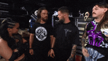a man wearing a t-shirt that says the ultimate warrior is standing next to two other men
