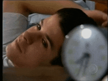 a man laying in bed with his head resting on an alarm clock that shows the time as 4:20