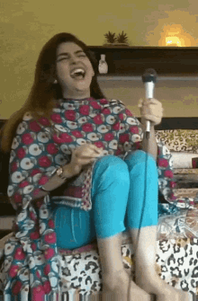 a woman is singing into a microphone and laughing