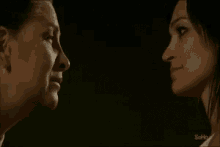 two women are looking at each other in a dark room with the word sofi on the bottom right corner .