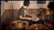 a man playing drums wearing a shirt that says ' evil ghost ' on it