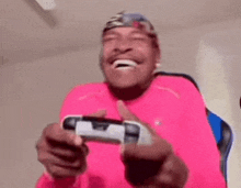 a man in a pink shirt is laughing while playing a video game .