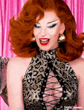 a woman with red hair is wearing a leopard print top with a lace up front
