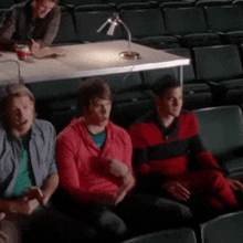 a group of young men are sitting in a theatre watching a movie