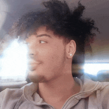 a young man with curly hair wearing a grey hoodie