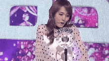 a woman is standing in front of a microphone that says ucrdee code on it