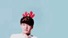 a young man wearing a reindeer headband is making a funny face .