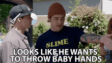 a man wearing a slime t-shirt talks to another man