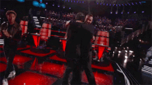 a group of men are hugging on a stage in front of a large crowd