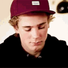 a young man wearing a red baseball cap is looking down .