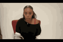 a woman wearing a black top and a red bra is sitting in a chair