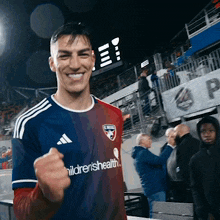 a man wearing a children 's health jersey holds his fist up