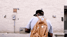 a man wearing a mcm backpack stands in front of a building