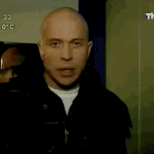 a bald man stands in front of a sign that says 33