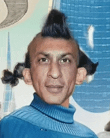 a man with a ponytail and a mohawk is wearing a blue sweater and looking at the camera .