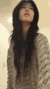 a woman with long hair is wearing a sweater and looking up at the sky .