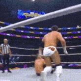 two men are wrestling in a ring with a referee watching .