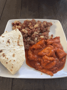 a plate of food with a tortilla and sauce on a wooden table