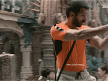 a man in an orange shirt with the word mercurialmess on the bottom right