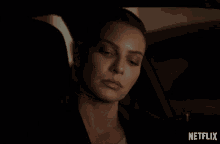 a woman sitting in a car with a netflix logo on the bottom