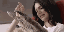 a woman is playing with a stuffed sloth while sitting on a couch .
