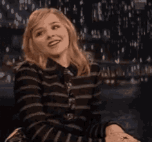 a woman is sitting on a couch and smiling .