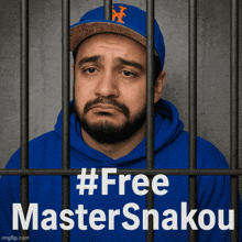 a man in a blue hoodie is behind bars with a sign that says #free master snakou