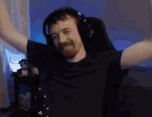 a man wearing headphones is sitting in a chair with his arms outstretched in a room .