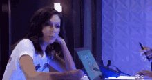 a woman is sitting at a table with a laptop and a pen in front of her .