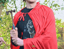 a man in a red cape holding a hammer with the word no embroidered on his shirt