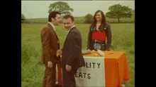 a man in a suit is shaking hands with another man in a field .