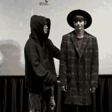 a man in a hoodie and a man in a hat are shaking hands .