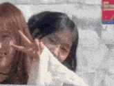 two girls are making a peace sign in front of a sign that says m-1