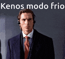 a man in a suit and tie is standing in front of a wall with the words kenos modo frio below him
