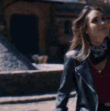 a woman wearing a leather jacket and a bandana looks up