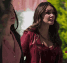 a woman in a red jacket stands next to a woman in a pink shirt