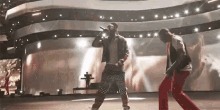 a man is singing into a microphone while another man is dancing