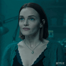 a woman wearing a necklace and a green sweater with a netflix logo in the corner
