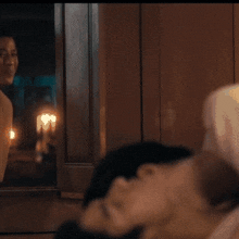 a man and a woman are looking out a window at a candle