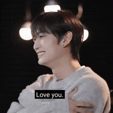 a man in a grey sweater says " love you " in a foreign language
