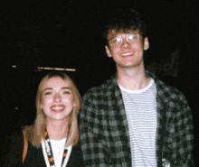 a man and a woman are posing for a picture and the woman has a lanyard around her neck that says ' planet '