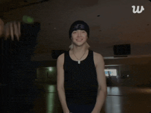 a man in a black tank top is dancing in front of a sign that says w.