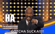 a man in a suit and tie is pointing at the camera and saying `` gotcha sucka ! ''